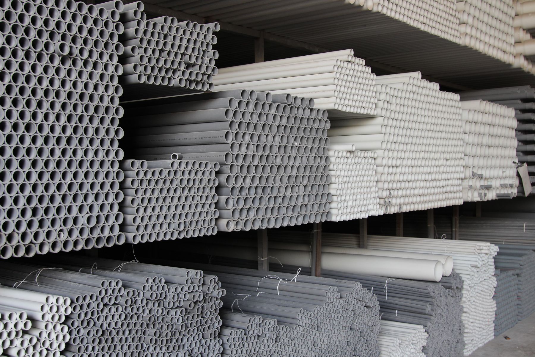 Deep aisle of grey and white PVC pipe bundles in storage